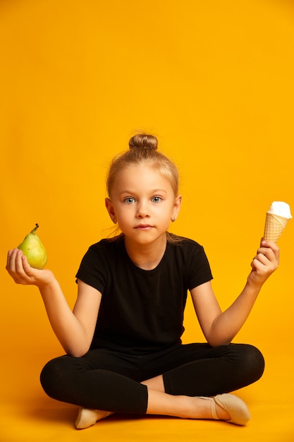 Verbaasde kleine danseres kiezen tussen peer en ijs