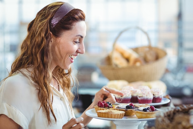 Verbaasde mooie vrouw die op cakes richt