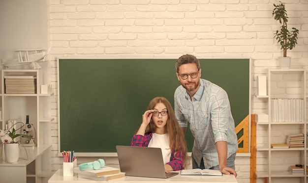 Verbaasde vader en kind studeren op school met laptop op schoolbord achtergrond e-learning