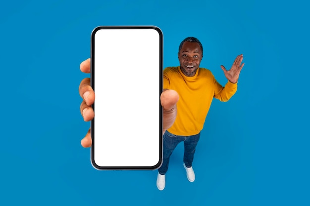Verbaasde volwassen zwarte man die smartphonemodel toont