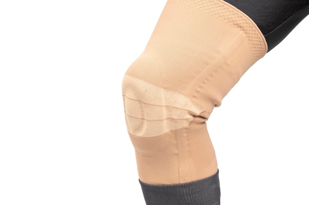 Verband voor het bevestigen van de geblesseerde knie van het menselijke been op een witte achtergrond. geneeskunde en sport. ledemaat letsel behandeling