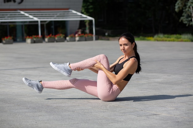 Verbazingwekkende gebruinde atletische vrouw die sportkleding draagt die rekoefeningen doet in het park