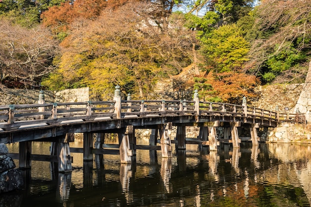 Verbazingwekkende oude houten brug van een Japans kasteel weerspiegeld in de gracht in de late namiddag, herfstbomen.