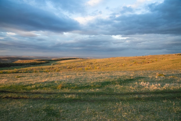 Verbazingwekkende zonsonderganghemel over groene heuvels in de vroege zomer