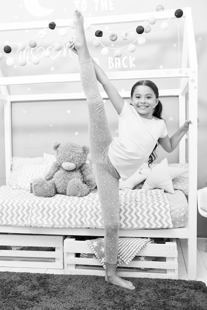 Foto verbeter de flexibiliteit meisje kind split in slaapkamer kind voorbereiden gaan naar bed meisje schattige pyjama ontspannen en strekken stretchen goed avond strekken leuke gymnast oefenen split voor het slapen gaan