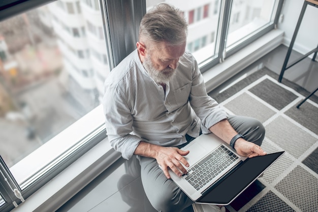 Verbonden. Een man die op de grond zit en op een laptop werkt