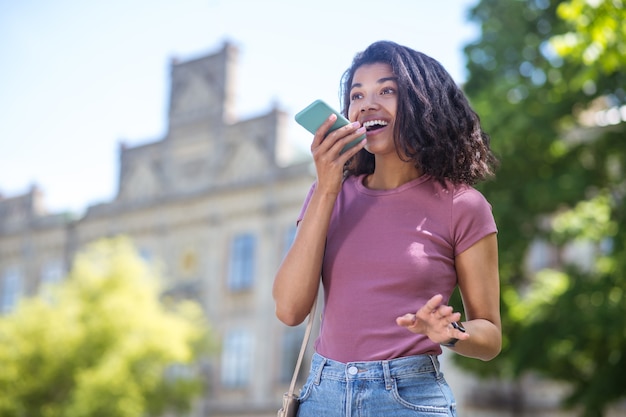 Verbonden. Mooie lachende mulatta met een smartphone die er leuk en gelukkig uitziet