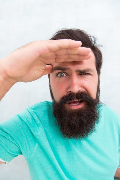 Verdachte blik. Man bebaarde hipster stijlvolle baard grijze achtergrond. Percepties van mannelijke schoonheid. Stijlvolle baard- en snorverzorging. Strikt gezicht. Baard mode kapper. Knappe vent. Mannelijkheid concept.