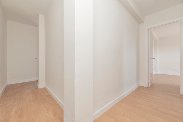 Verdeelgangen in een leegstaand huis met houten vloeren en effen wit geschilderde muren