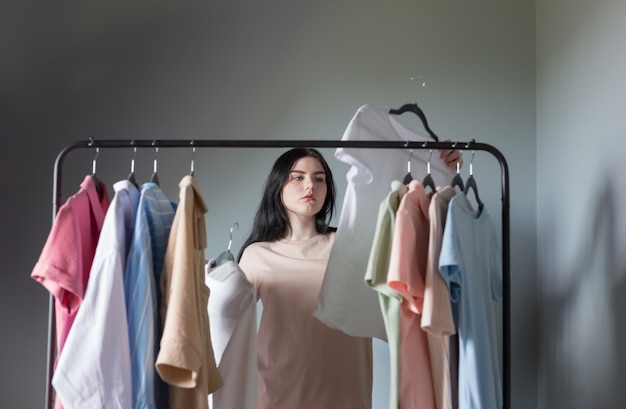 Verdrietig jong meisje naast zomerkleren op hanger thuis