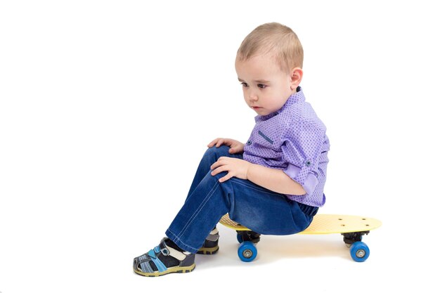 Verdrietig kind zittend op een skateboard, moe en slaperig