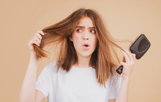 Verdrietig meisje met beschadigd haar Haaruitval probleembehandeling Portret van vrouw met een kam en probleemhaar