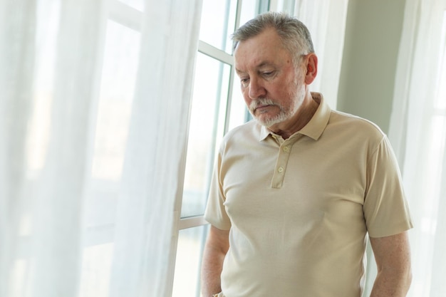 Verdrietig moe eenzaam teleurgesteld oudere senior man alleen thuis ongelukkige grootvader die droevig outsi kijkt