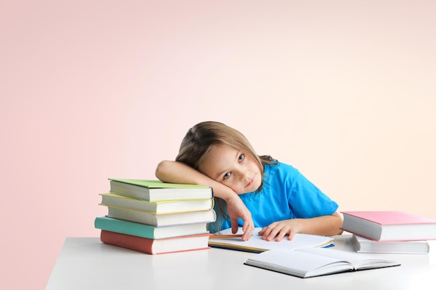 Verdrietig moe studentenmeisje zittend aan tafel met veel boeken