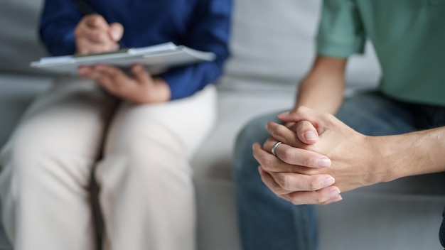 verdrietige man zit op de bank patiënt bespreekt psychische problemen met psycholoog depressieve Aziatische man psychische gezondheidsbehandeling