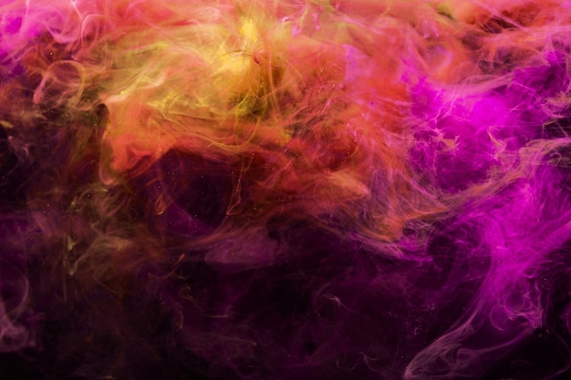 Verf in water. Kleurrijke achtergrond. Abstracte stoom textuur. Gloeiende levendige neon magenta roze paars oranje mist mix die zich op het donker verspreidt.