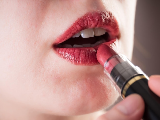 Verf je lippen met felrode lippenstift. Detailopname. Lip make-up