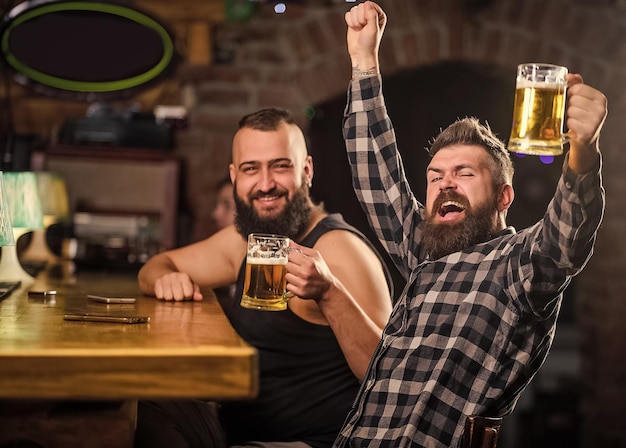 Verfrissend bier concept Hipster brutale man bier drinken met vriend aan toog Mannen dronken ontspannen plezier Alcohol drankjes Vrienden ontspannen in pub met bier Mannen samen bier drinken