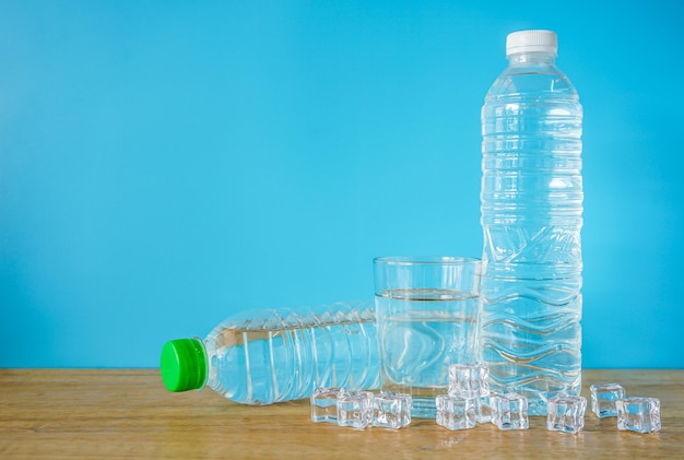 Verfrissend natuurlijk mineraalwater in plastic fles met transparant glas en ijsblokjes