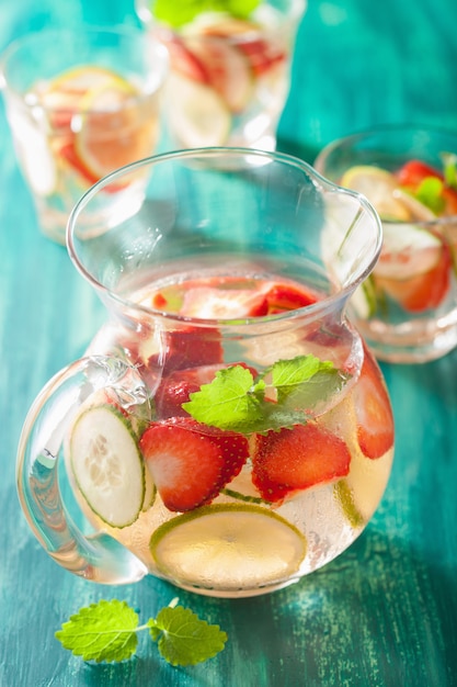 Foto verfrissend zomerdrankje met aardbeien komkommer limoen in pot en glazen