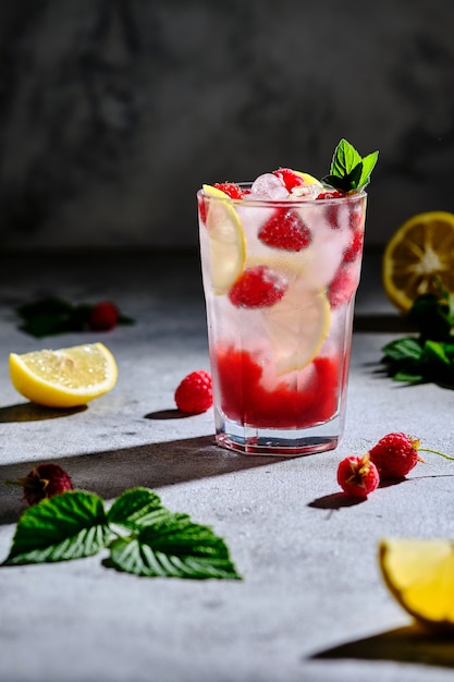 Verfrissende alcoholische zomercocktail met frambozenlikeur en citroen. IJsdrank gegarneerd met munt en verse bessen.