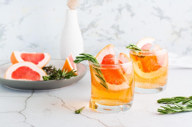 Verfrissende grapefruitcocktail met rozemarijn in glazen en fruit op een bord op tafel Zelfgemaakte drank