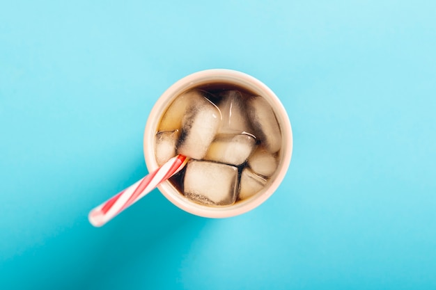 Verfrissende ijskoffie in een glas op een blauwe ondergrond. Concept zomer, cola met ijs, verfrissende cocktail, dorst. Plat lag, bovenaanzicht