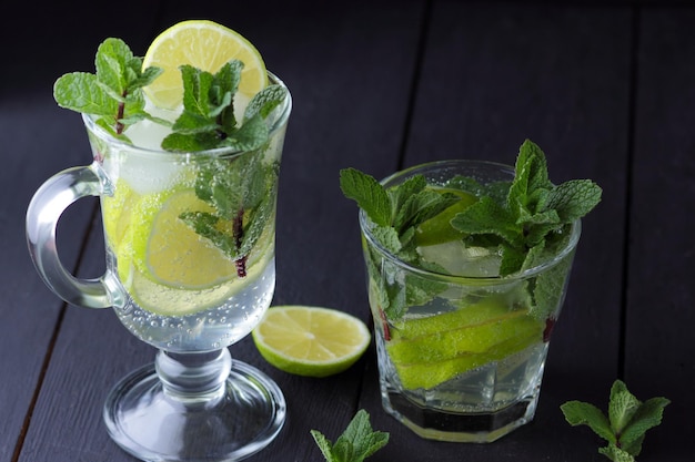 Verfrissende koude mojito in een hoog glas met ijs munt citroen en limoen op een zwarte achtergrond close-up