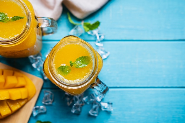 Verfrissende mango smoothies in glas met rijpe mango op houten lijst en copyspace, Hoogste mening