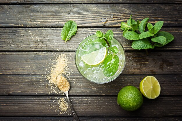 Verfrissende muntcocktailmojito met rum en limoen, koud drankje of drank met ijs op wit houten oppervlak, bovenaanzicht