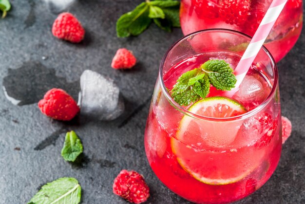 Verfrissende non-alcoholische cocktails in de zomer. vruchtendranken. frambozenmojito limonade met verse biologische munt en limoen. op een zwarte stenen tafel. kopieer ruimte