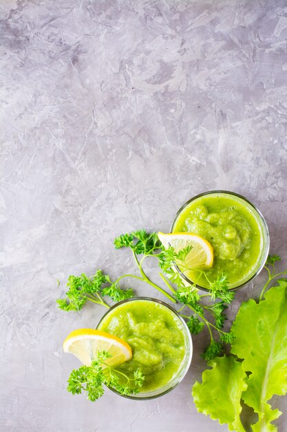 Verfrissende smoothies van komkommer, groene appel, verse kruiden en citroensap in transparante glazen op tafel. Het concept van een gezond dieet. Vegetarisch menu. Bovenaanzicht