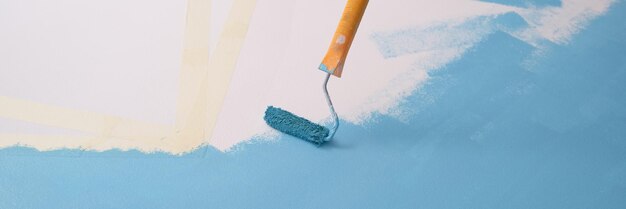 Verfroller schildert witte muur met blauwe kleur kopieerruimte voor verbetering van tekstkunst en