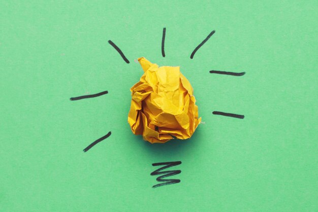Verfrommeld geel papier laightbulb als concept creatief idee en innovatie op een groene achtergrond