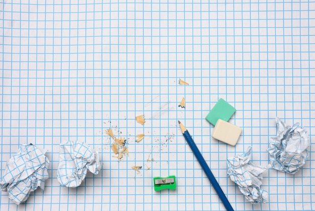 Verfrommeld papieren ballen en een geslepen houten potlood met schaafsel op een geruit vel papier