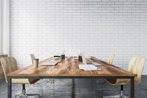 Vergaderruimte interieur met witte bakstenen muren, een betonnen vloer, grote ramen en een lange houten tafel met houten stoelen ernaast. Zijaanzicht. 3D-rendering mock-up