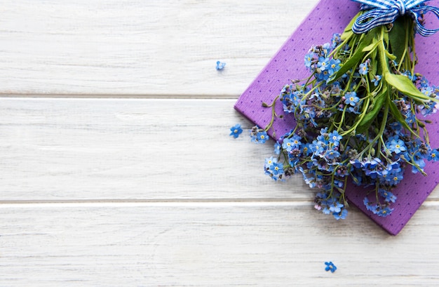 Vergeet-mij-nietjebloemen en notitieboekje op een witte houten lijst