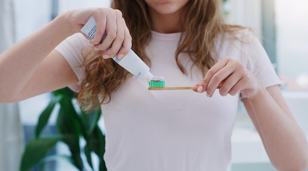 Vergeet niet twee keer per dag je tanden te poetsen Shot van een jonge vrouw die tandpasta op een tandenborstel aanbrengt