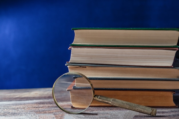 Vergrootglas in de buurt van oude boeken op donkerblauw