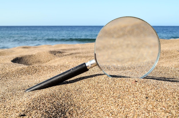 Vergrootglas op het zandstrand