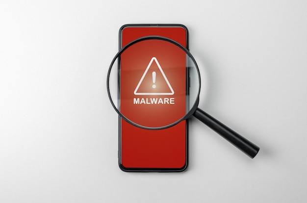 Vergrootglas op mobiele telefoon een alarmbord dat malware detecteert Beveiligingsconcept voor mobiele telefoons Viruswaarschuwing Zoeken naar malware