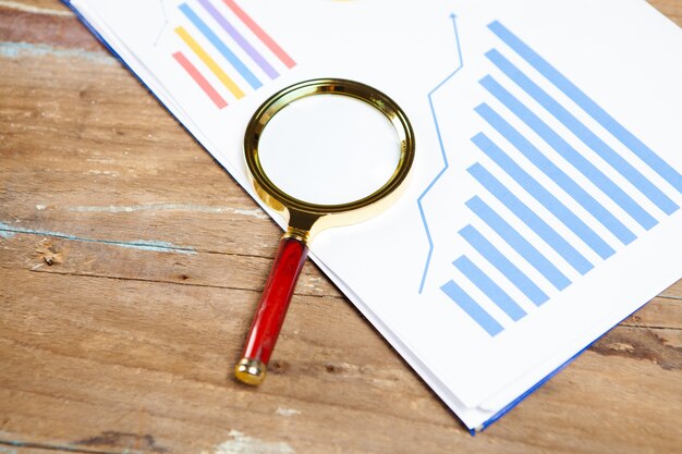 Vergrootglas op statistische grafieken op tafel