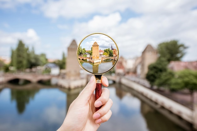 Vergrootglas vasthouden gericht op de oude toren aan de rivier in Straatsburg in Frankrijk