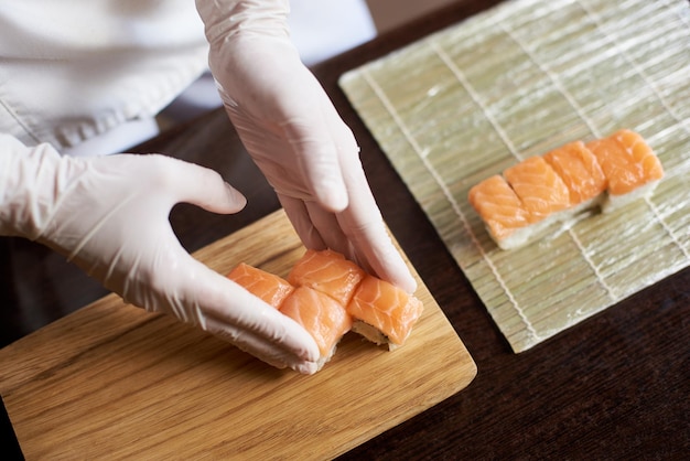 Vergrote weergave van het proces van het bereiden van rollende sushi. Chef serveert heerlijke verse broodjes op de houten plank