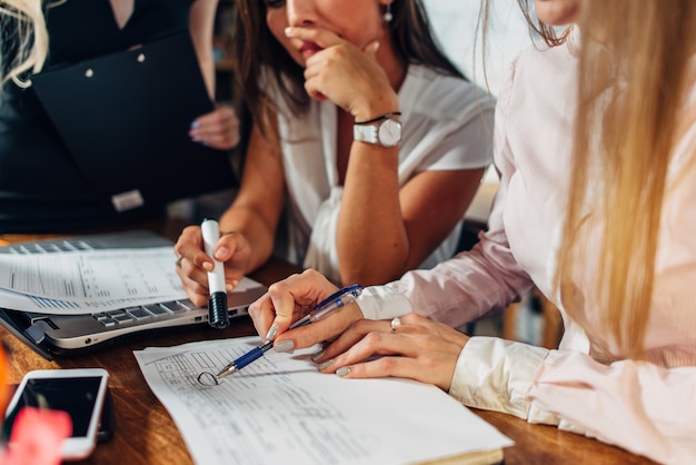 Vergrote weergave van jonge vrouwen die bezig zijn met het controleren van boekhoudpapier en wijzend op documenten.