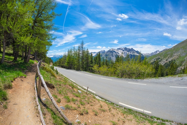 Verharde weg met twee rijstroken in schilderachtig alpien landschap en humeurige hemel, fisheyemening. Zomeravontuur en roadtrip in Col d'Izoard, Frankrijk.