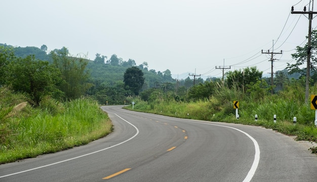 Verharde weg ThailandDe asfaltweg aan beide kanten van de weg is bedekt met gras