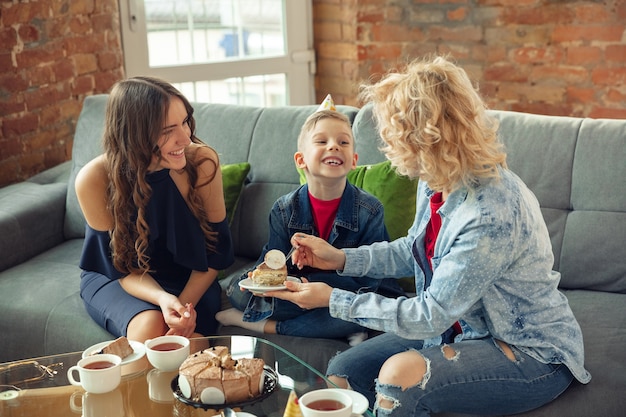 Verheugd. Moeder, zoon en zus hebben thuis plezier. Vakantie, familie, comfort, gezellig concept, verjaardag vieren. Mooie Kaukasische familie. Tijd samen doorbrengen, spelen, lachen groet