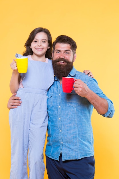 Verhoog het energieniveau Klein kind en vader houden kopjes warme energiedrank vast Gelukkig gezin geniet 's ochtends van koffie Energie stimuleren Hallo ochtend