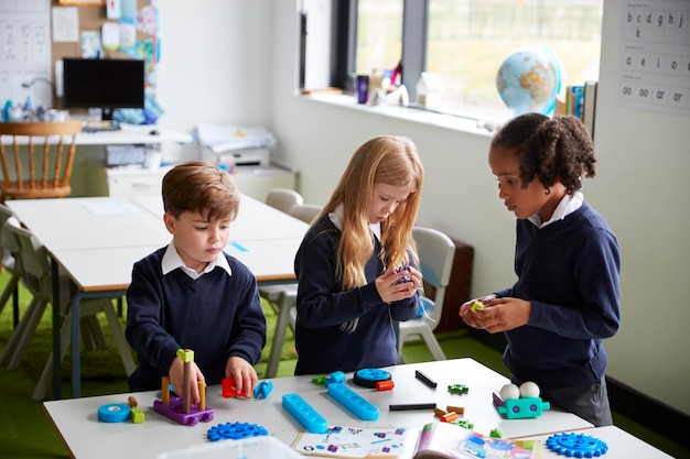 Verhoogde weergave van drie basisschoolkinderen die samenwerken met behulp van bouwblokken in een klaslokaal